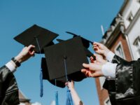 people holding their graduation hats up