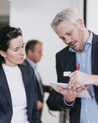 man showing woman something on paper - both wearing suits